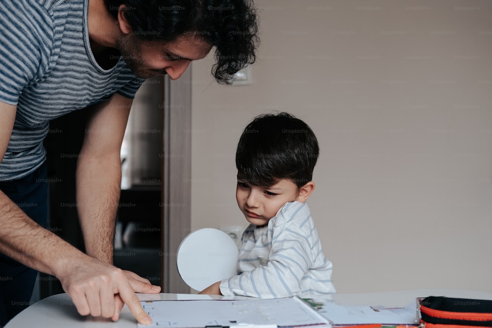Un hombre ayudando a un niño con un pedazo de papel