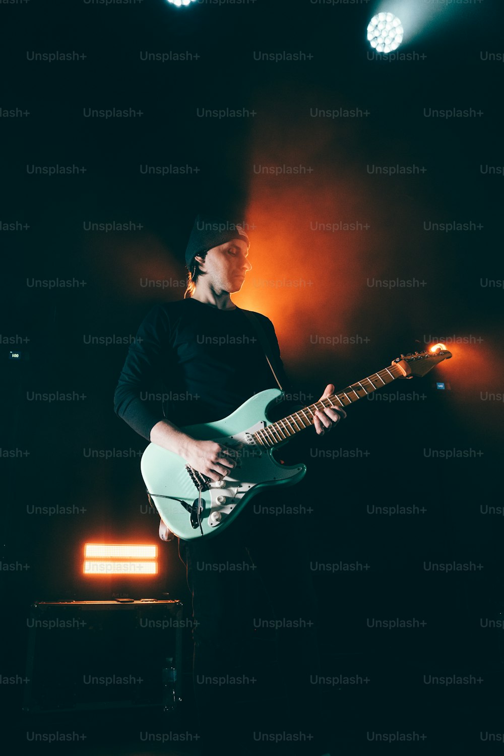 a man playing a guitar in a dark room