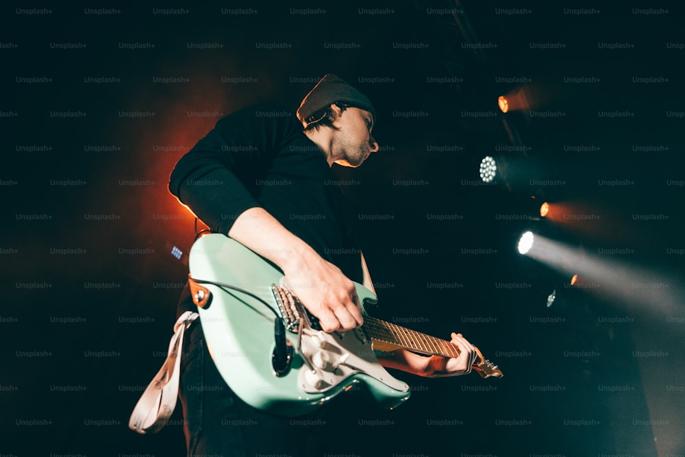 Un homme jouant de la guitare sur scène lors d’un concert