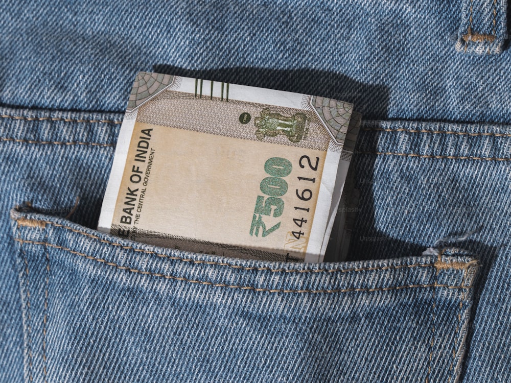 uma nota de dinheiro saindo do bolso traseiro de uma calça jeans