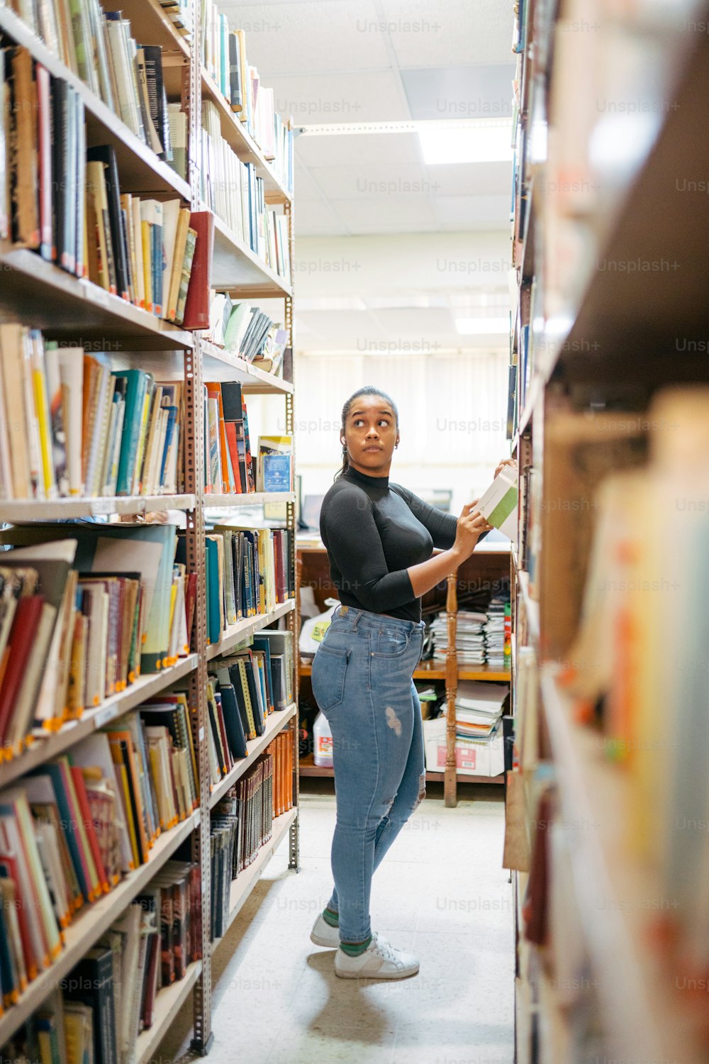 a woman standing in a library holding a book