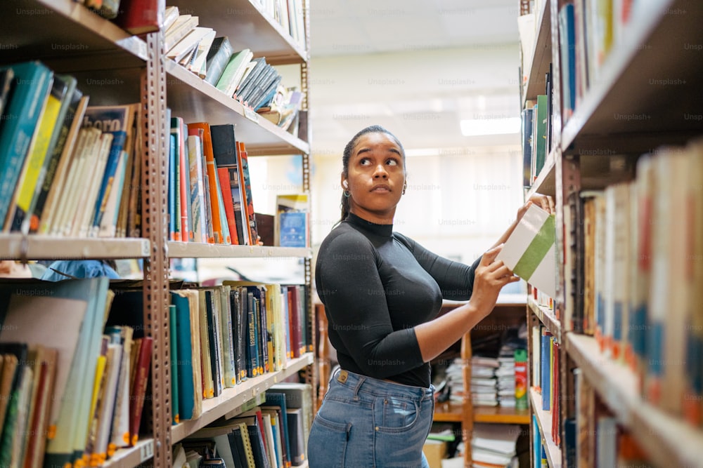 Una donna in piedi in una biblioteca con in mano un libro