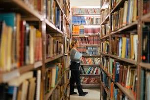 uma mulher de pé em uma biblioteca cheia de muitos livros