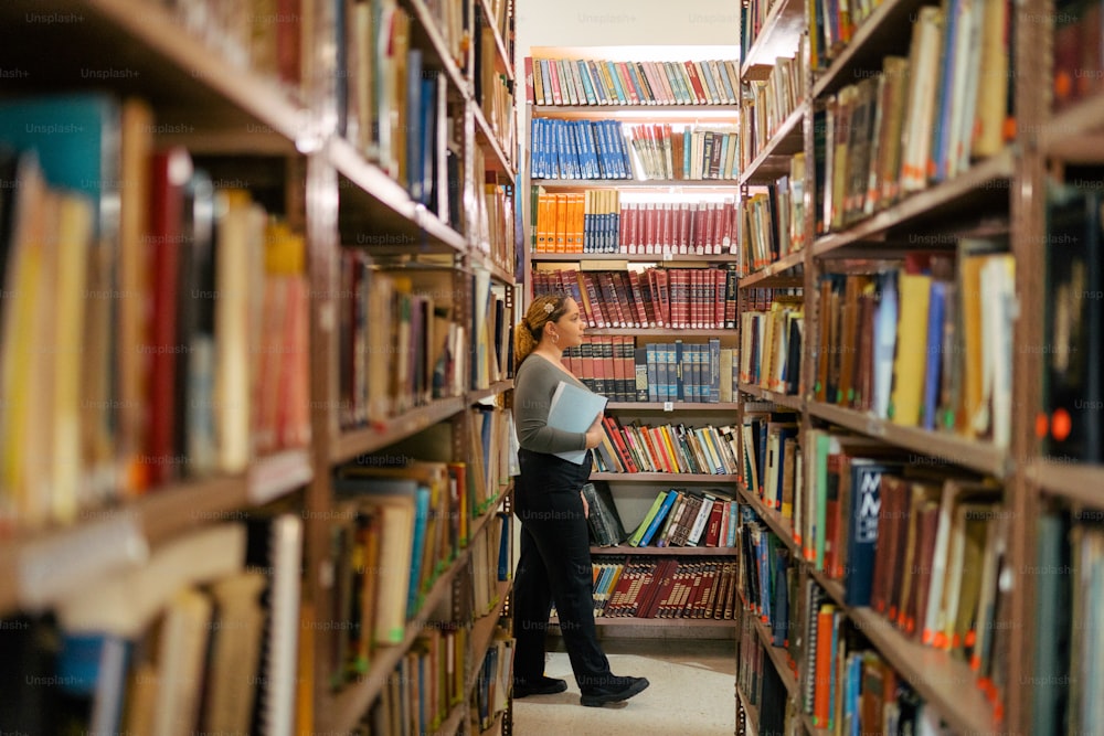 uma mulher de pé em uma biblioteca cheia de muitos livros