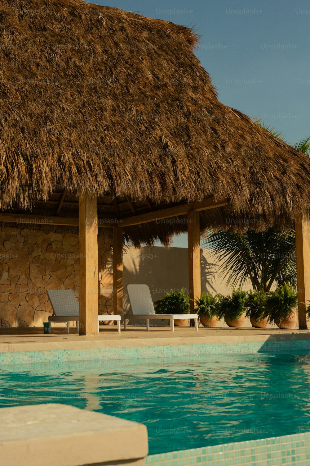 a thatched roof next to a swimming pool