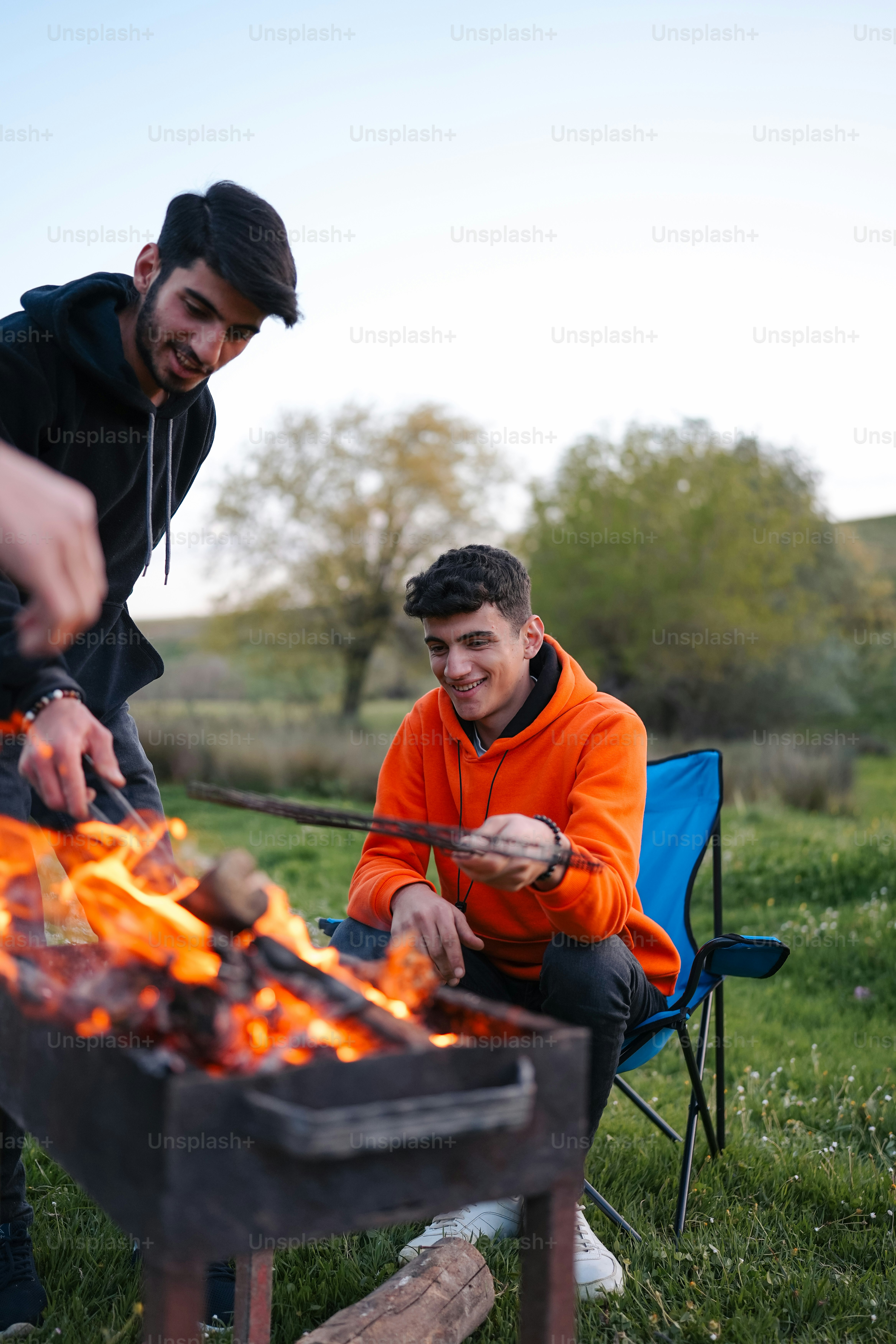 a couple of men sitting around a fire pit