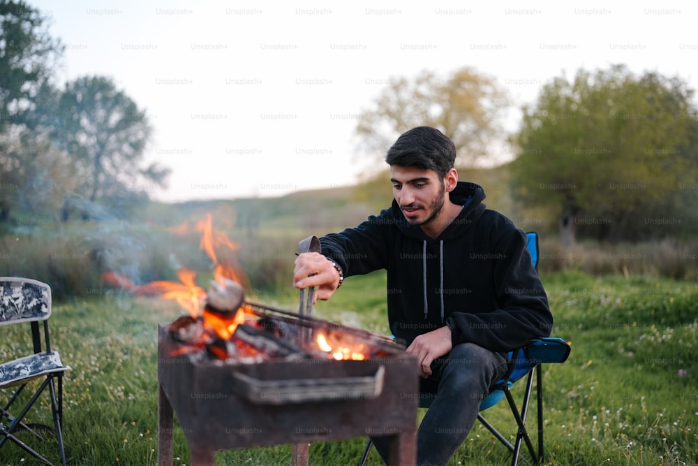 Un uomo seduto su una sedia accanto a un pozzo del fuoco
