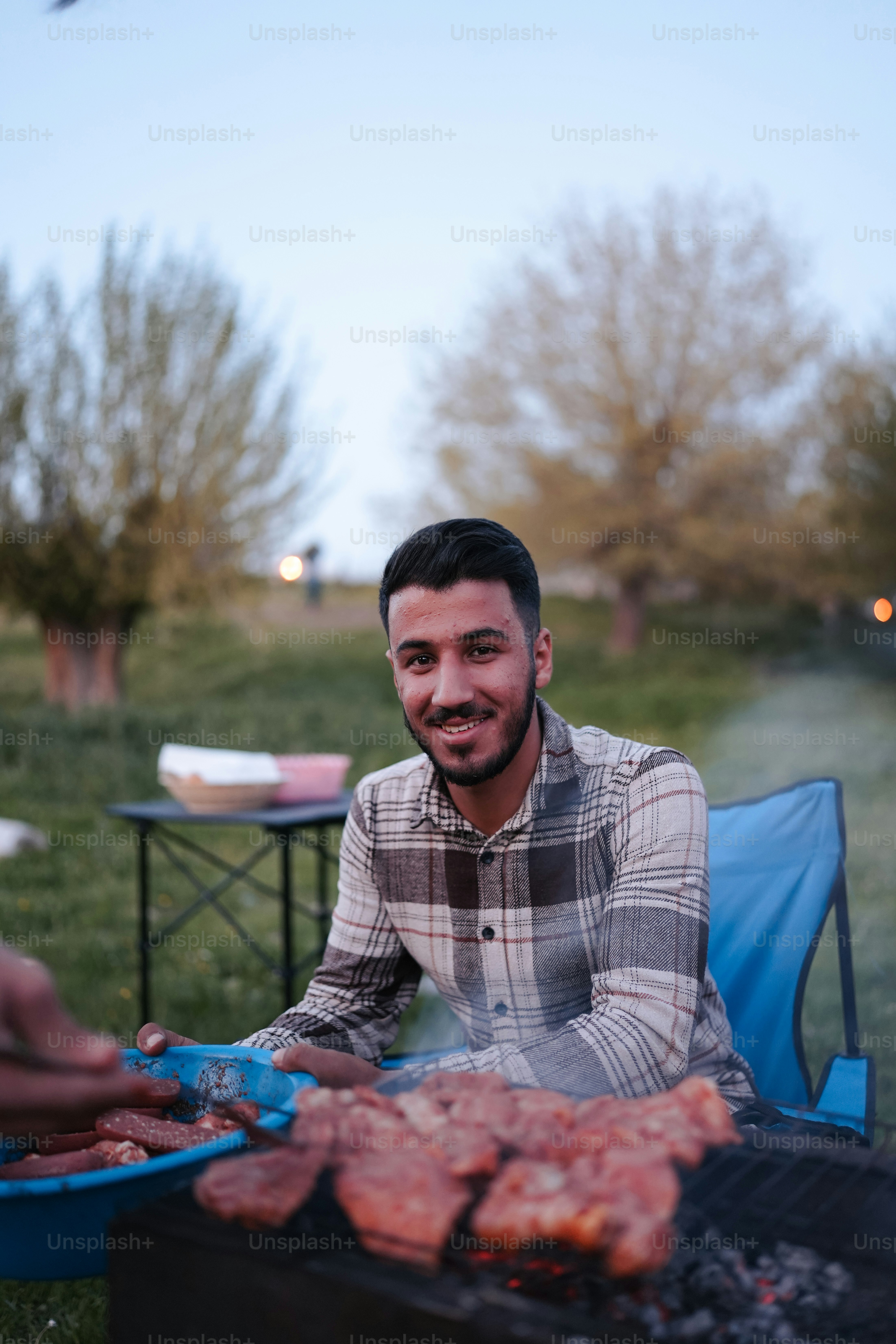 a man sitting in a chair next to a grill