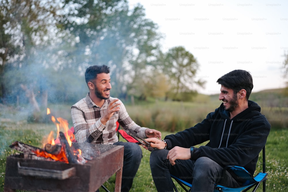 a couple of men sitting around a fire pit