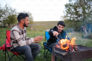 a couple of men sitting next to a fire pit