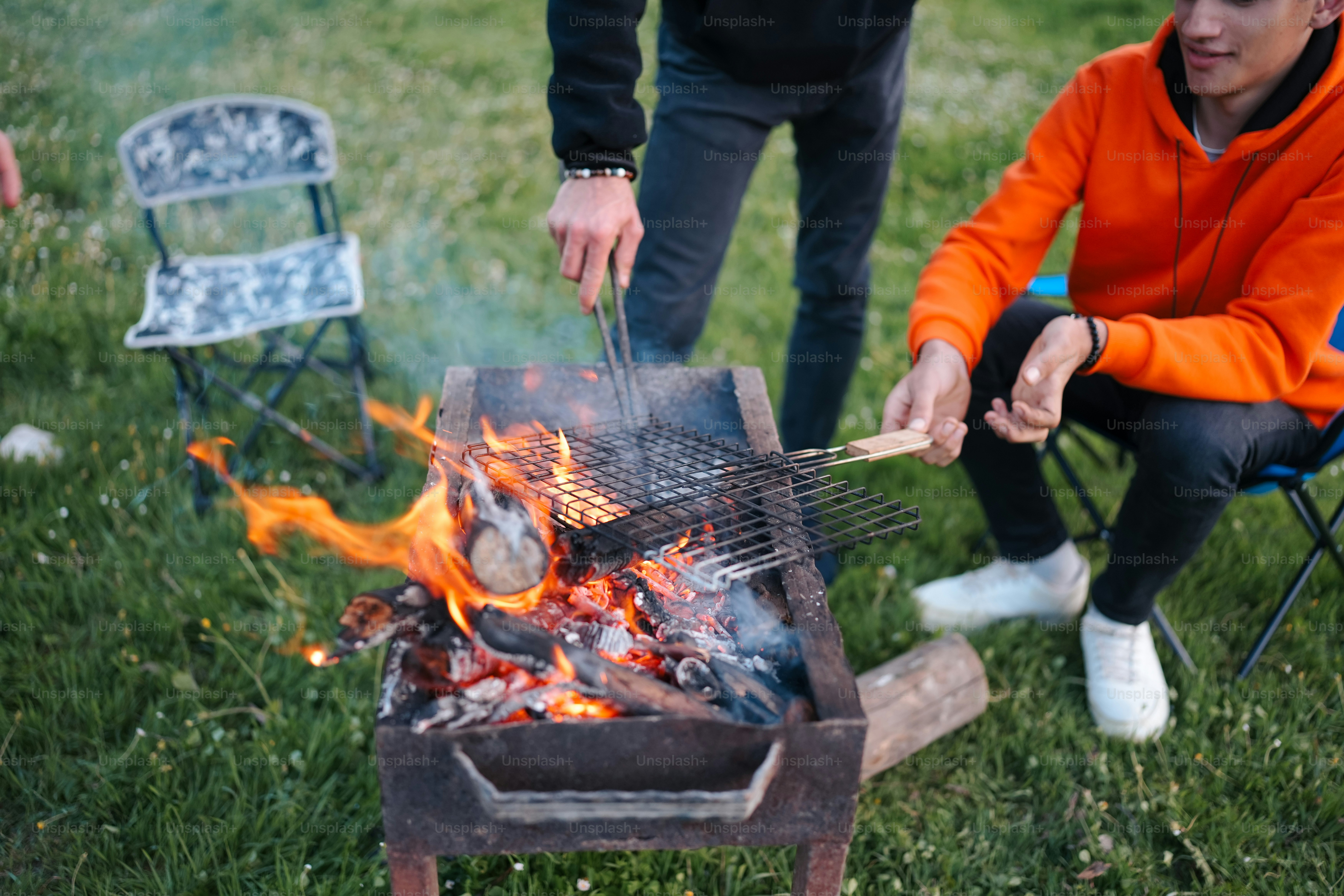a man is cooking on a grill in the grass