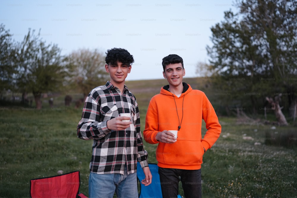 two young men standing next to each other in a field