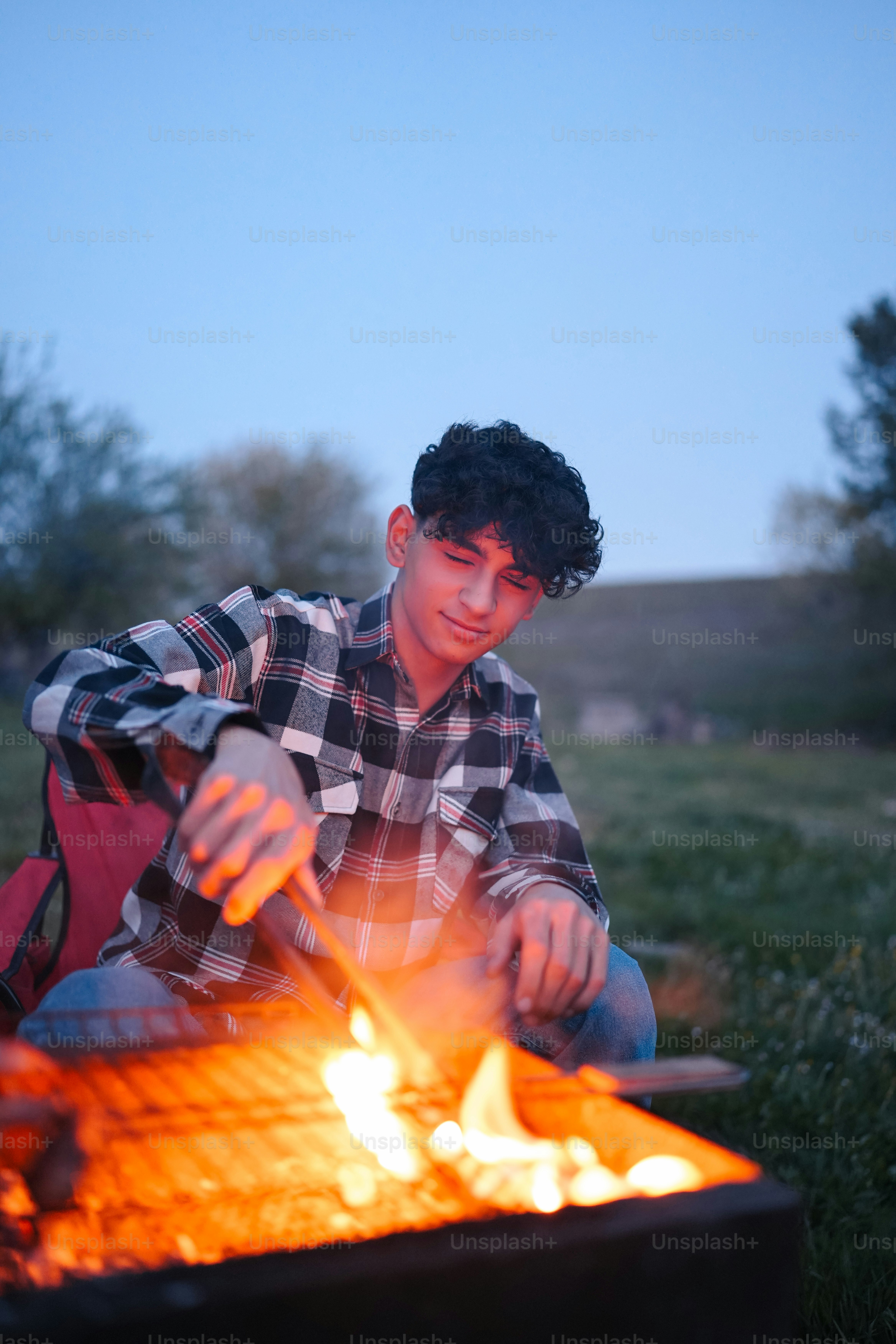 a young man sitting in front of a fire pit