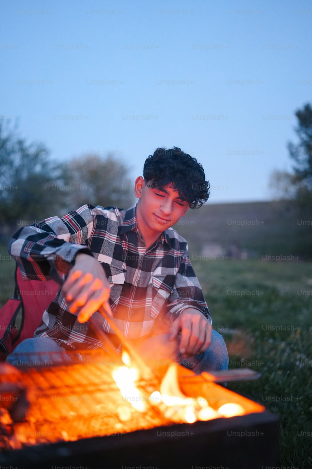 a young man sitting in front of a fire pit