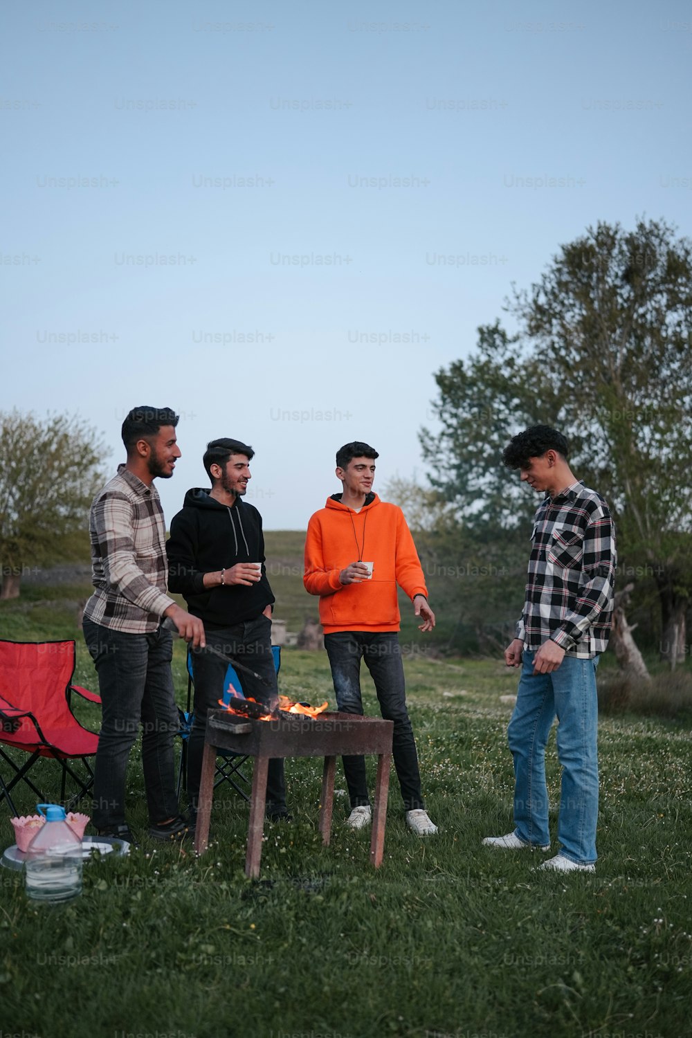 a group of young men standing around a campfire