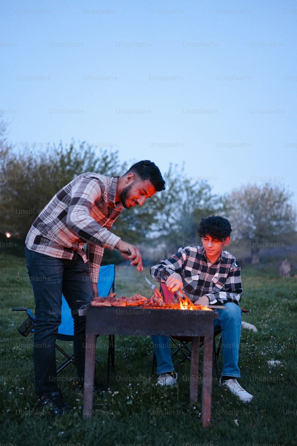a man and a boy sitting around a fire pit