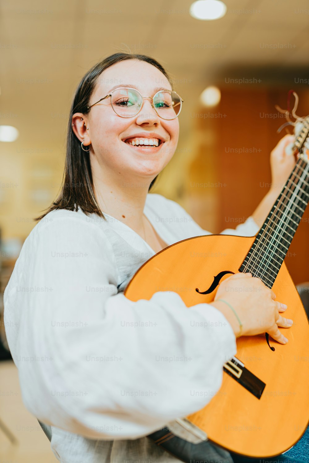 Una mujer sosteniendo una guitarra en una habitación