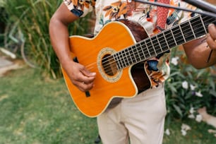 Un hombre sosteniendo una guitarra en su mano derecha