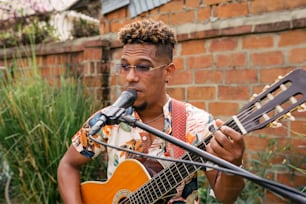 Un hombre tocando una guitarra y cantando en un micrófono