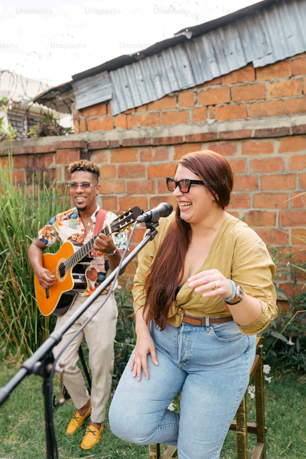Un hombre y una mujer tocando la guitarra frente a un micrófono