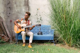 a man sitting on a blue bench playing a guitar