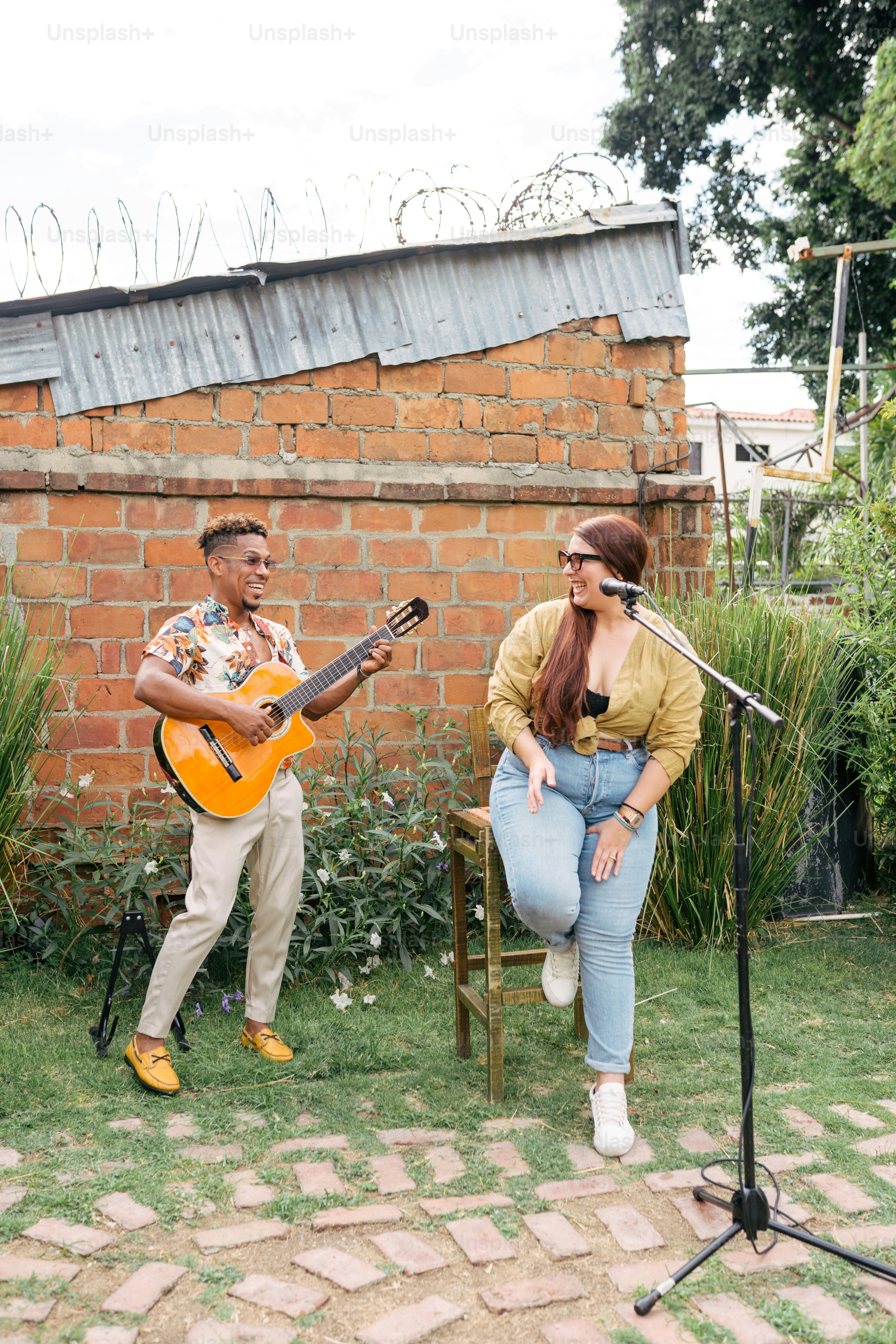 Un hombre y una mujer están tocando la guitarra afuera