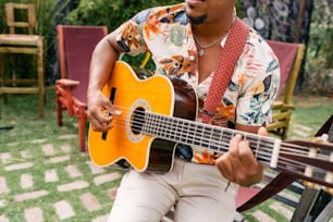 a man sitting on a chair playing a guitar