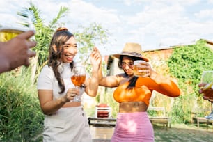 a group of women standing next to each other holding wine glasses