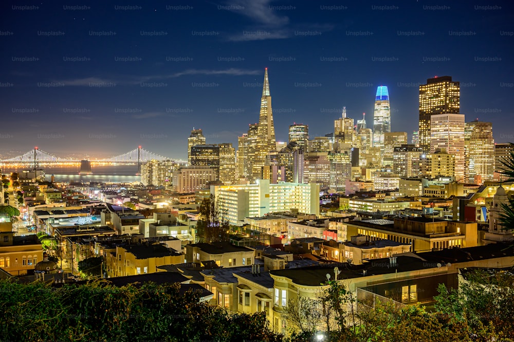 uma vista de uma cidade à noite com uma ponte ao fundo