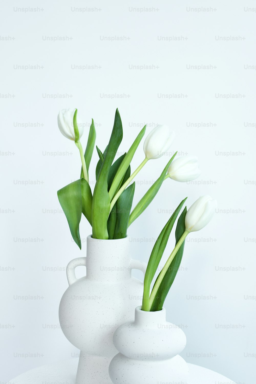 테이블 위에 꽃이 든 세 개의 흰색 꽃병