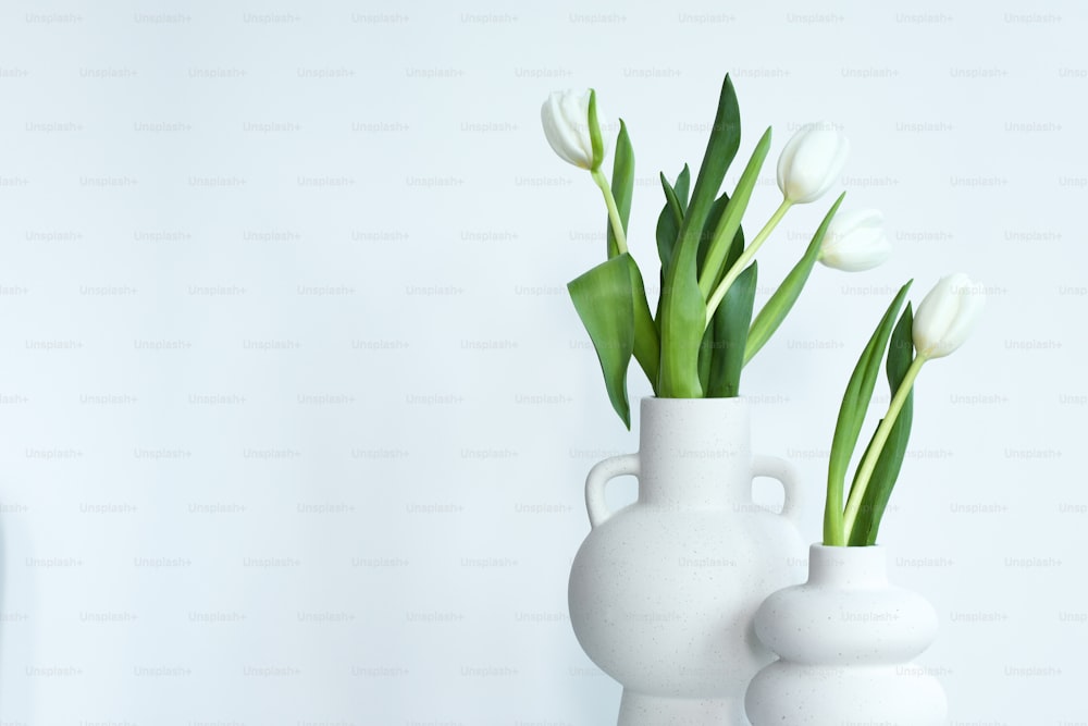 a couple of white vases with flowers in them