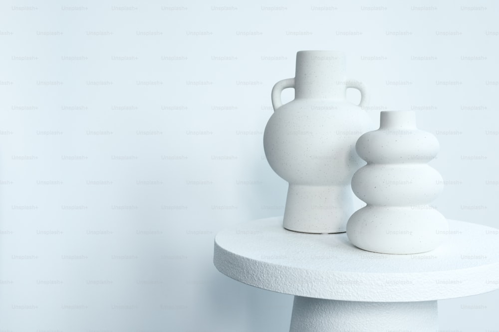 two white vases sitting on top of a white table