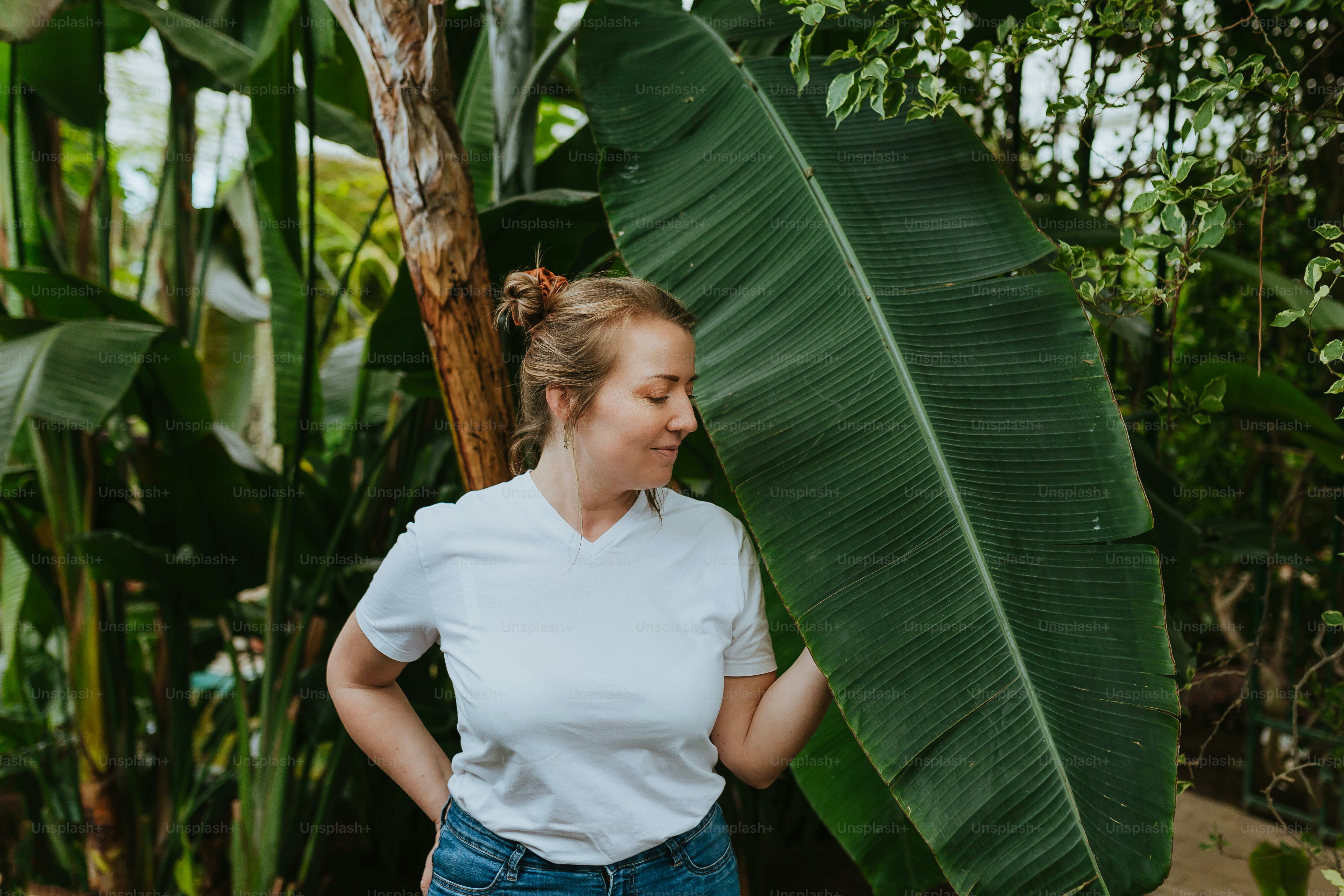 Una donna in piedi accanto a una grande foglia verde