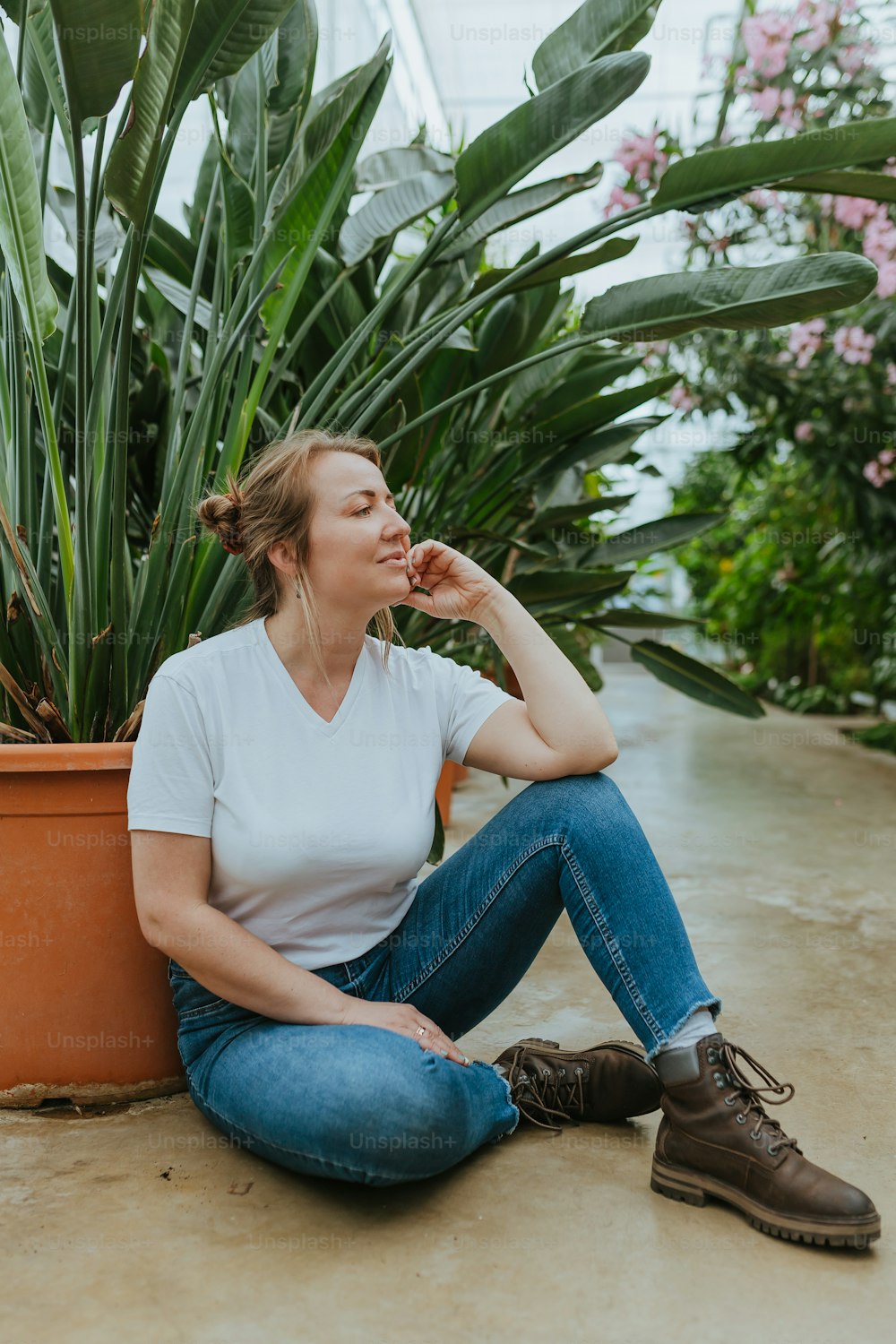 a woman sitting on the ground next to a potted plant