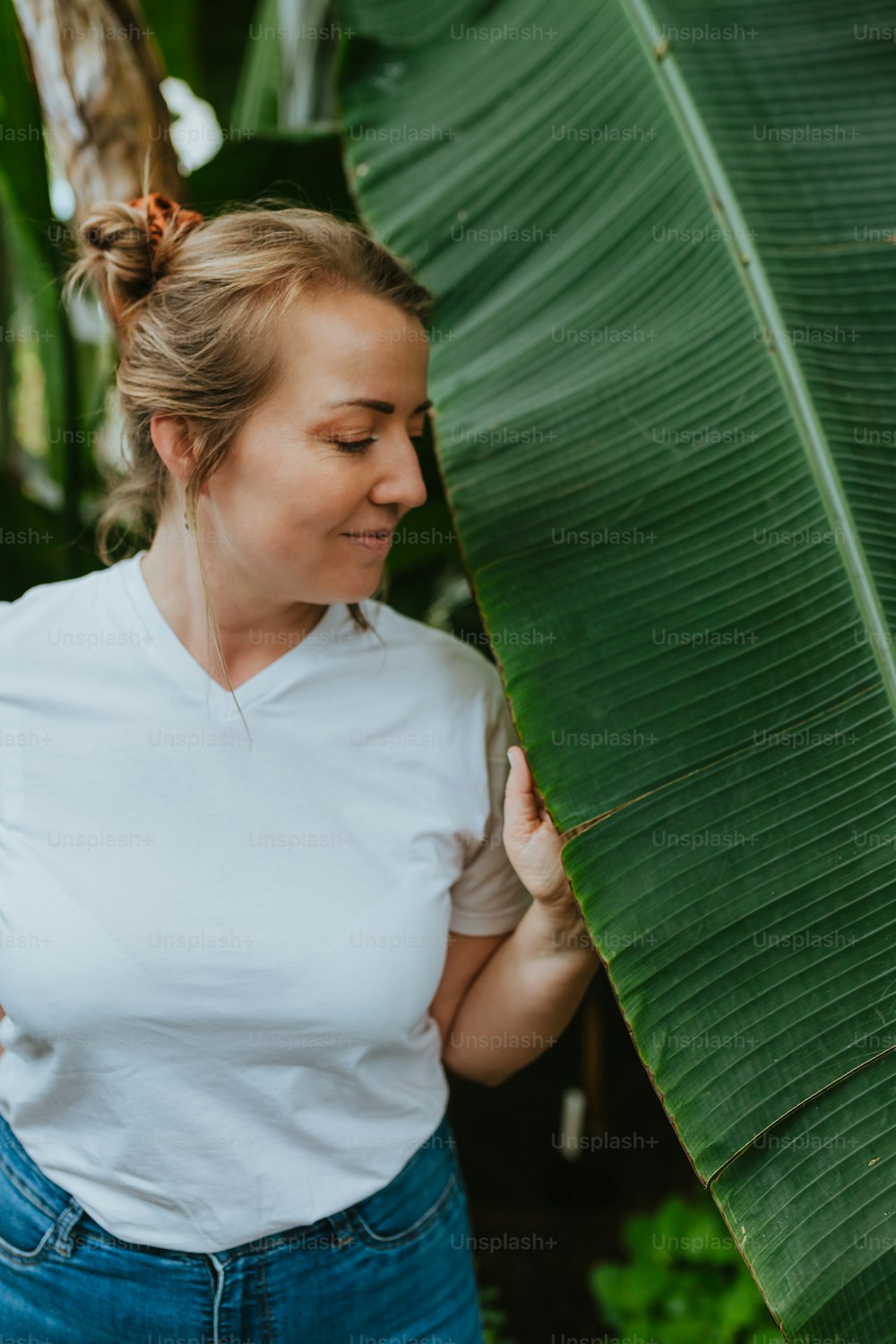 Une femme debout à côté d’une grande feuille verte