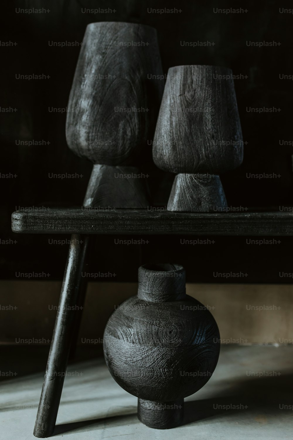 um vaso preto sentado em cima de uma mesa de madeira
