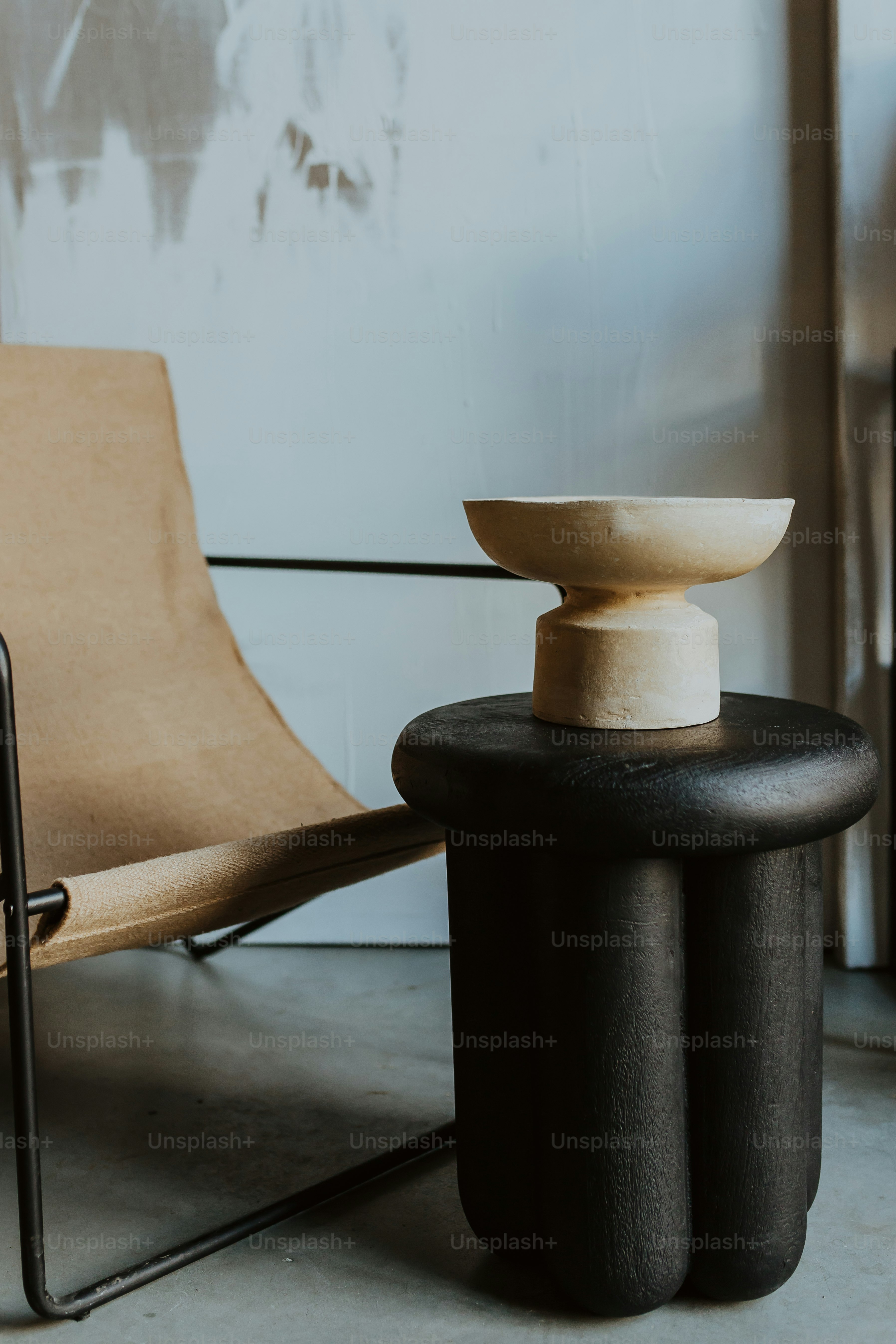 a chair sitting next to a table with a bowl on top of it