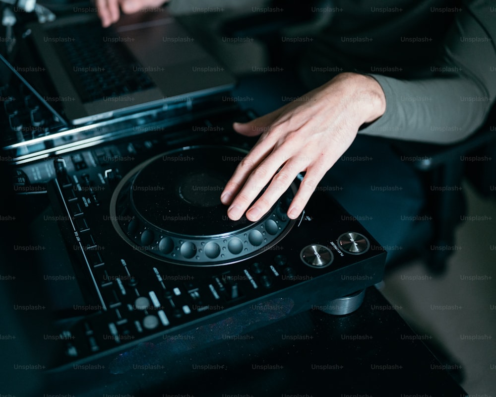 Una persona usando una computadora portátil encima del tocadiscos de un DJ