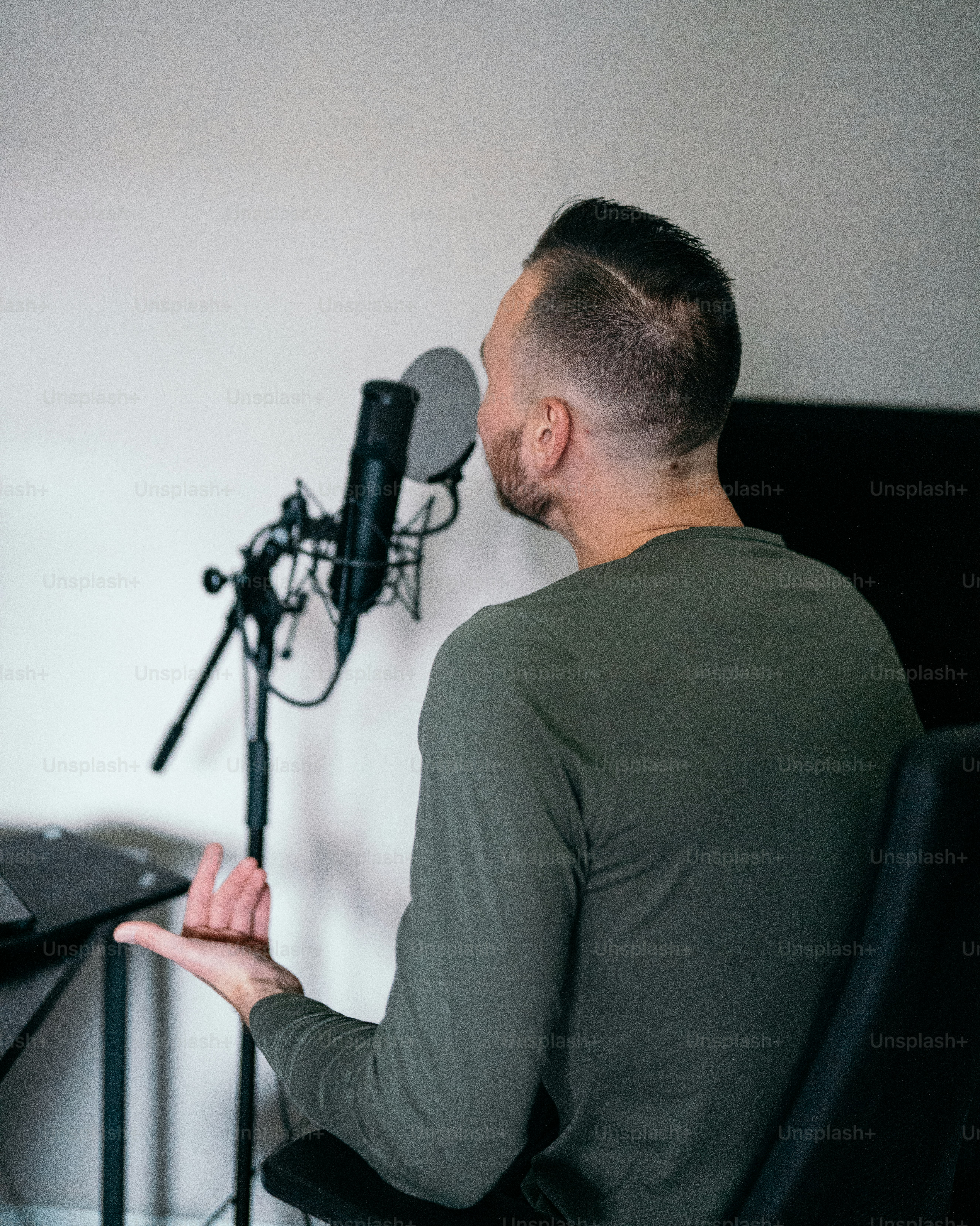 マイクの前の椅子に座っている男性