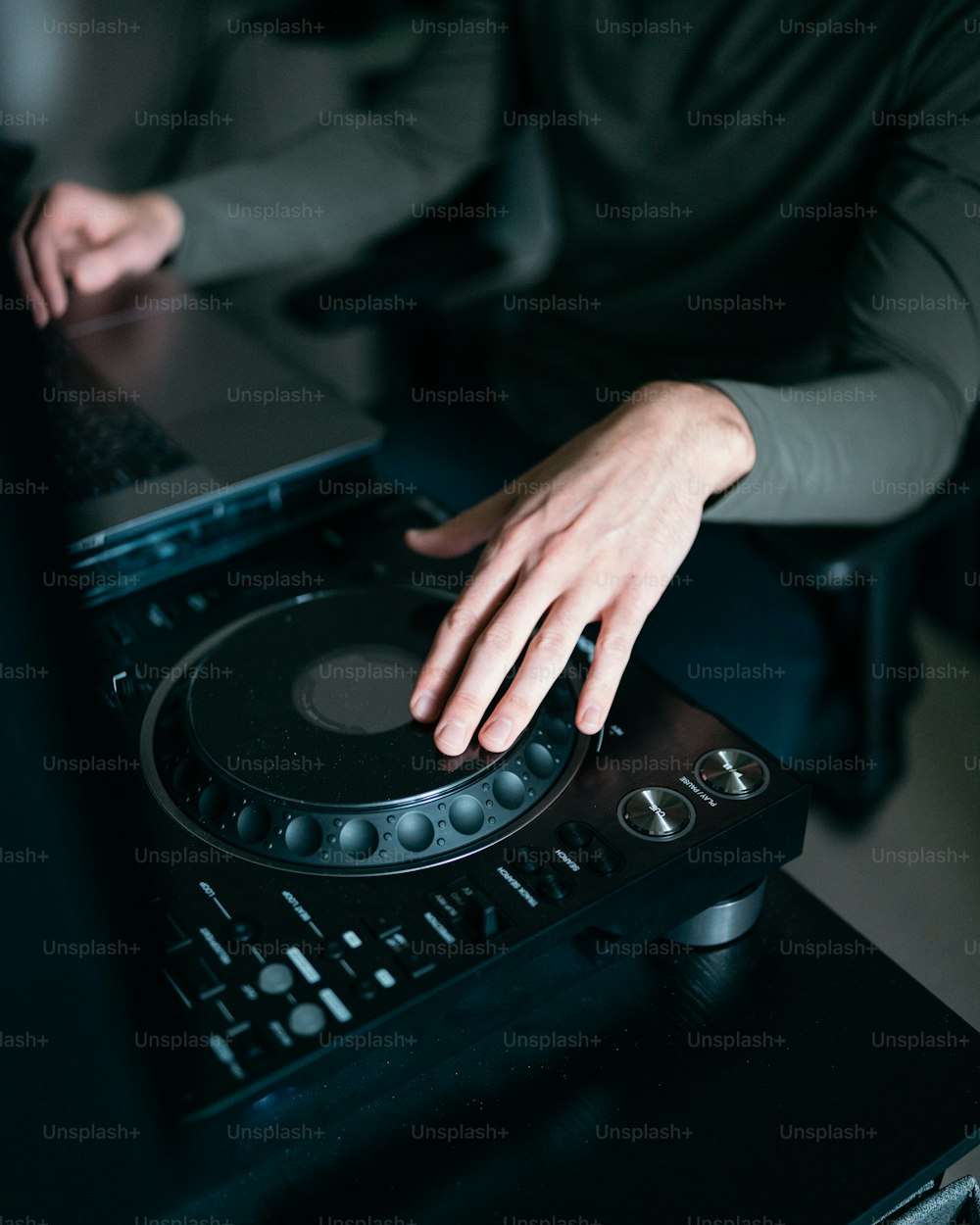 Una persona usando el tocadiscos de un DJ frente a una computadora portátil