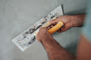 Un uomo sta dipingendo un muro con un rullo di vernice