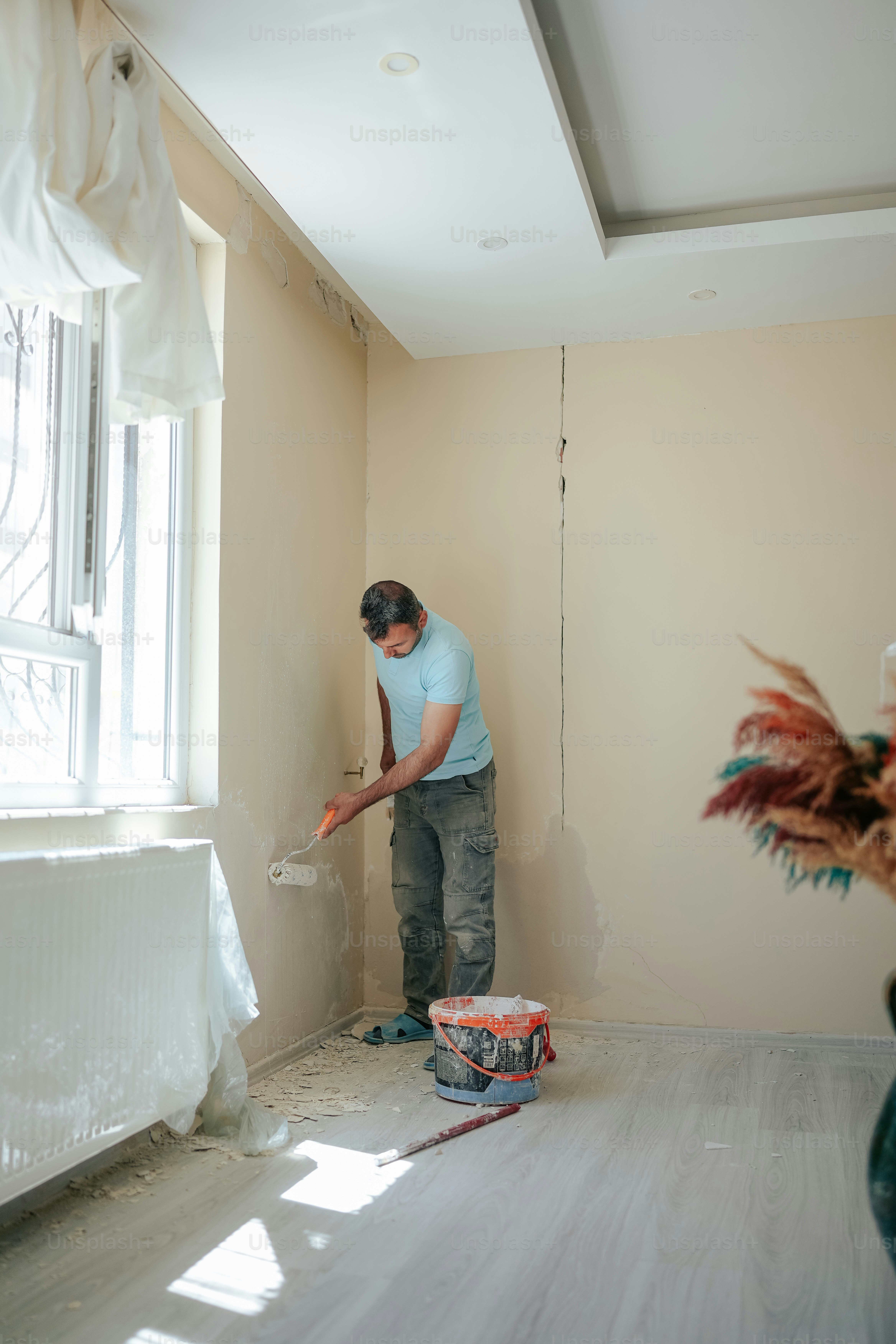 a man in a blue shirt is painting a room