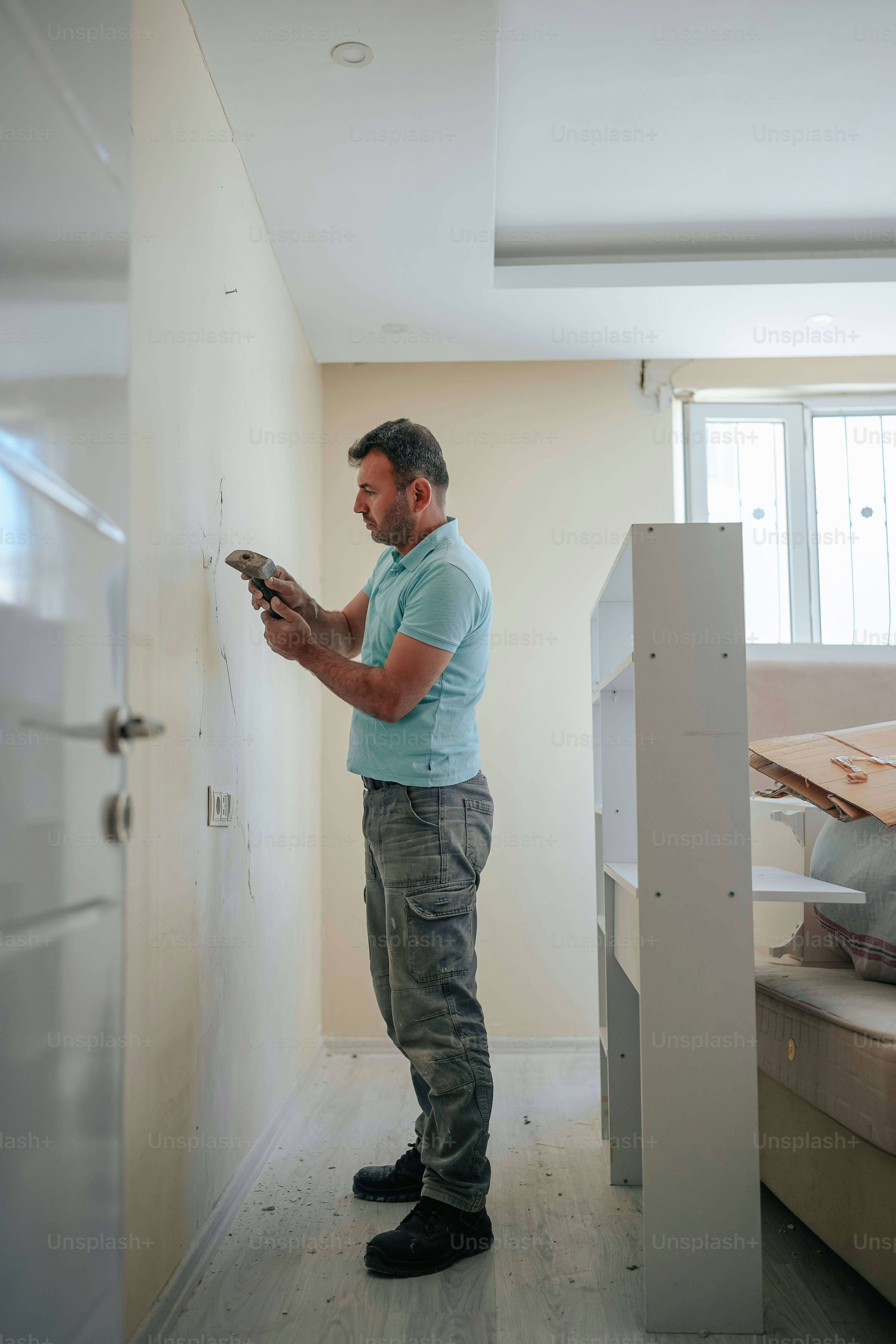 a man standing in a room holding a hammer
