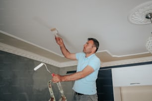 a man painting a ceiling with a paint roller