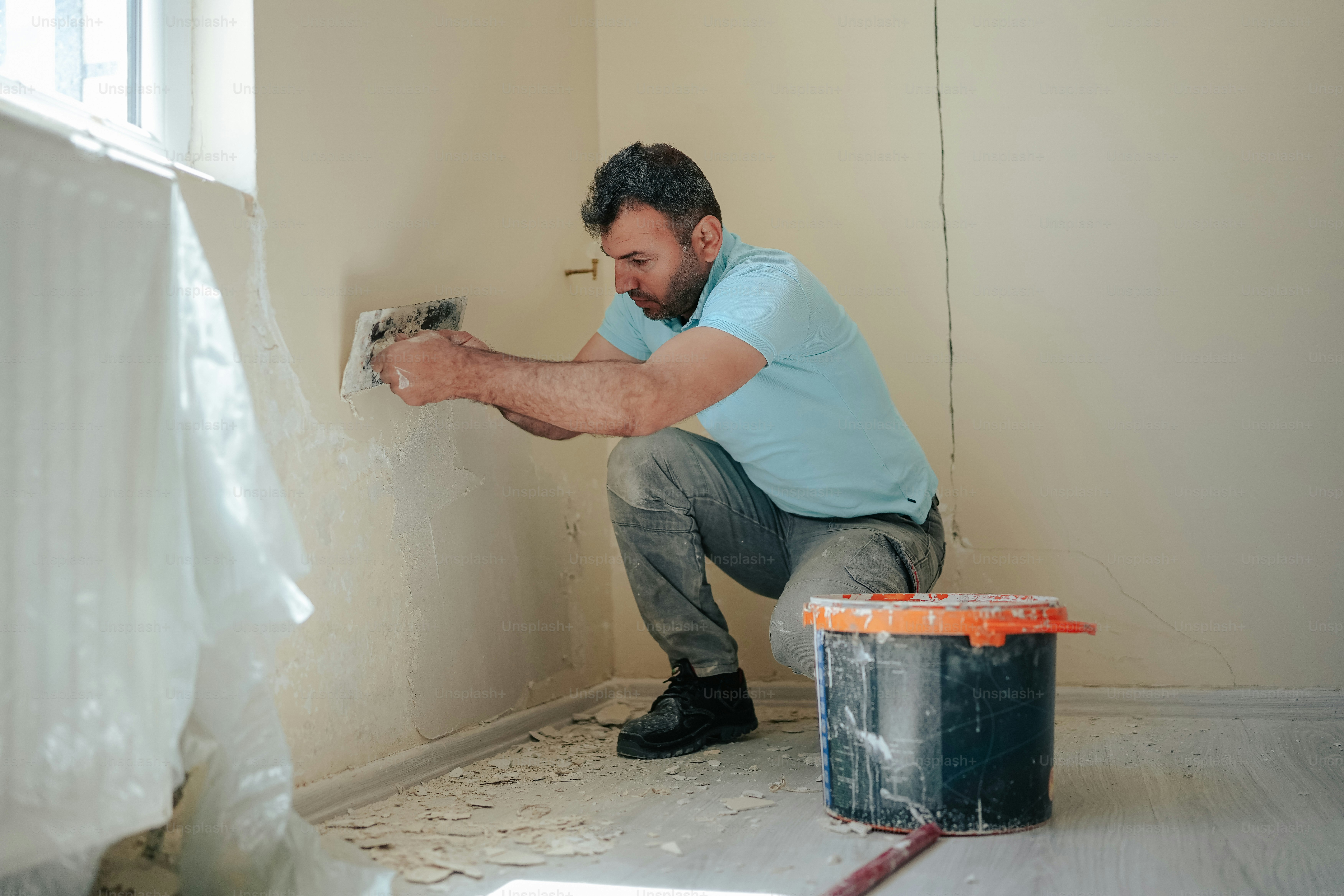 Un homme peignant un mur avec un rouleau de peinture