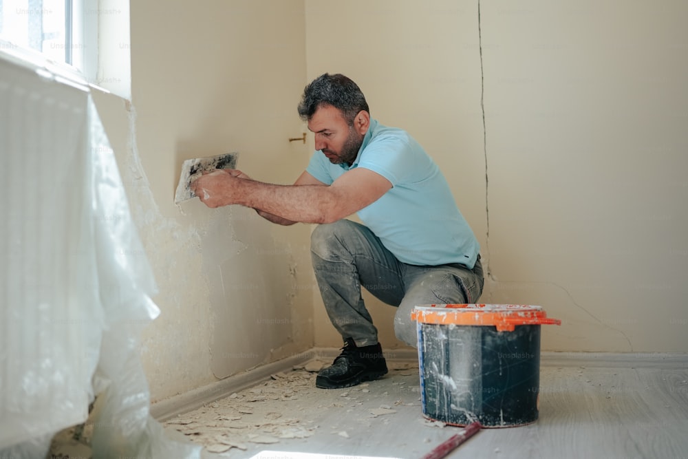 a man painting a wall with a paint roller