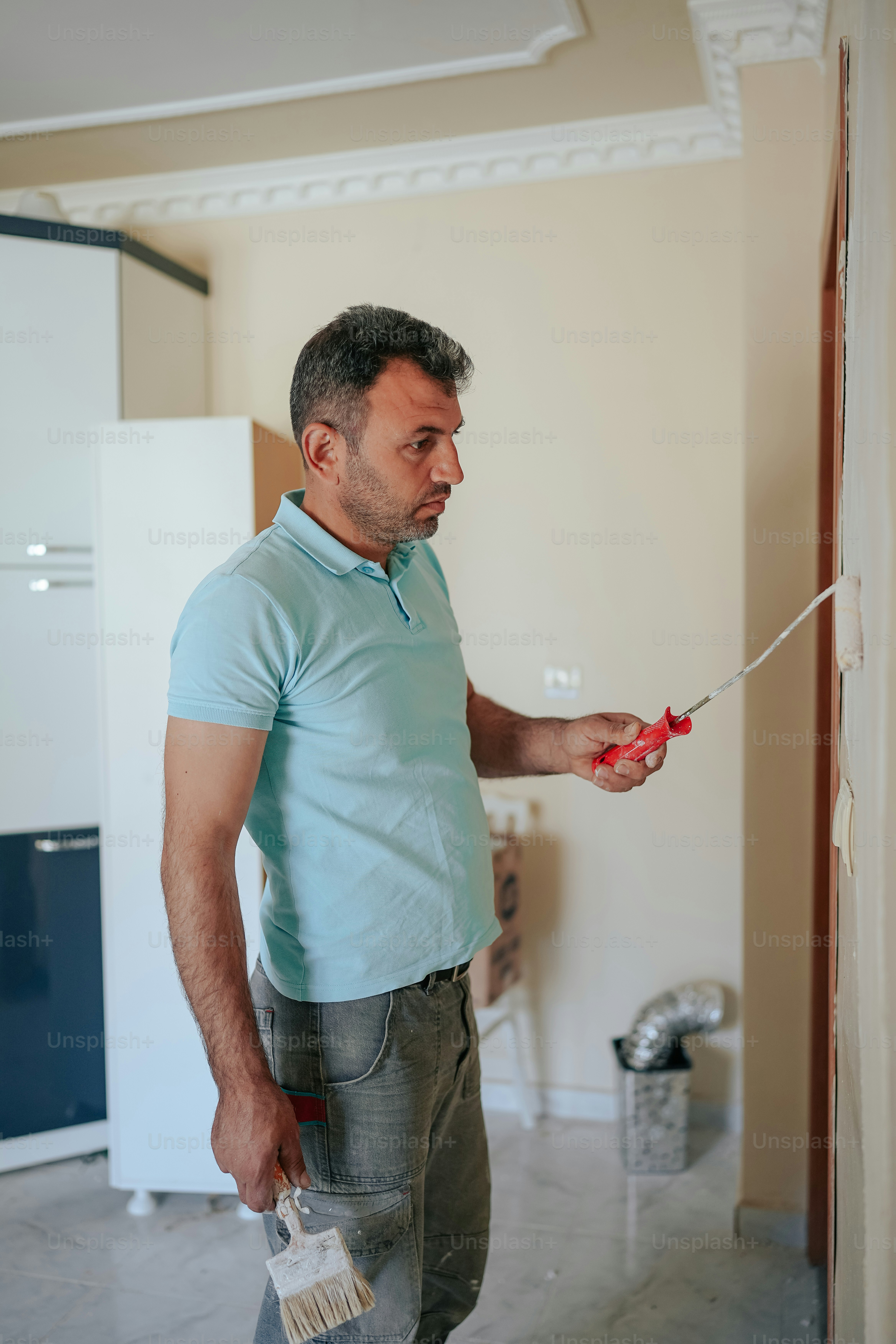 Un homme en chemise bleue peint un mur
