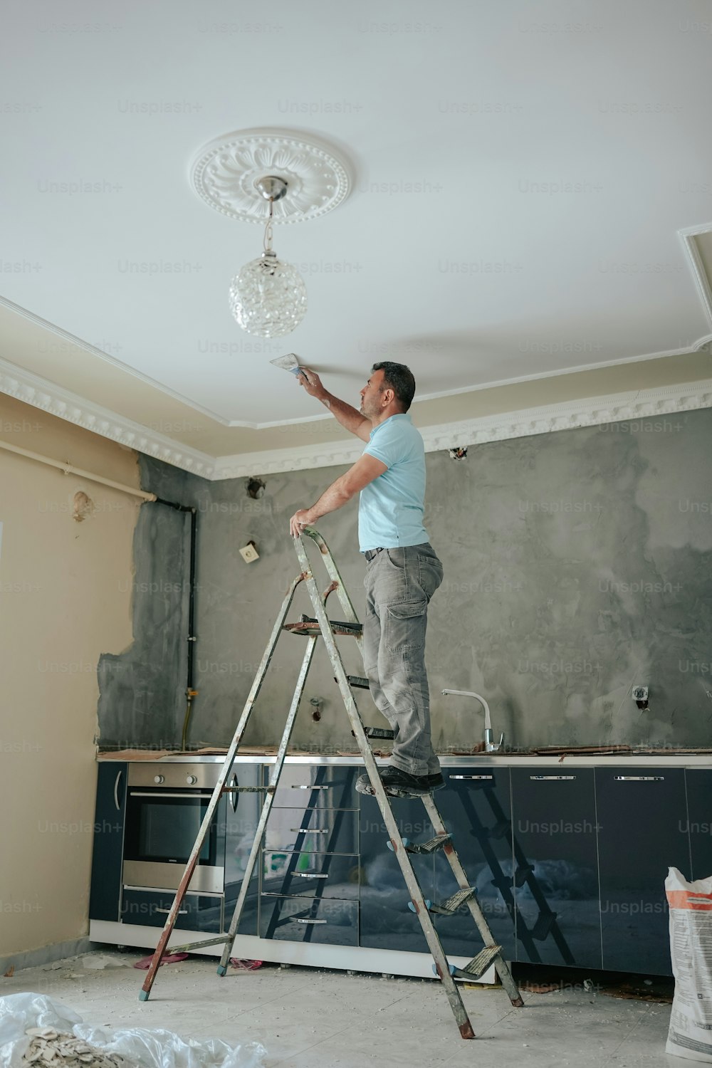 a man standing on a ladder painting a wall