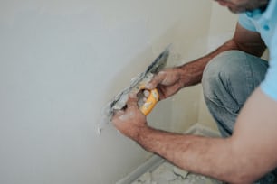 a man working on a wall with a paint roller