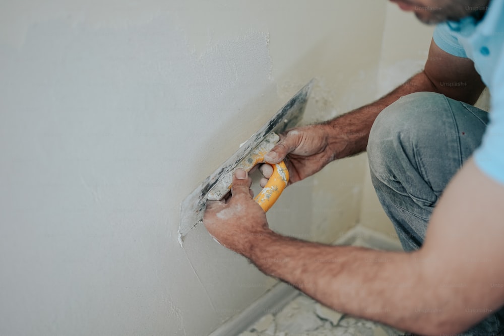 a man working on a wall with a paint roller